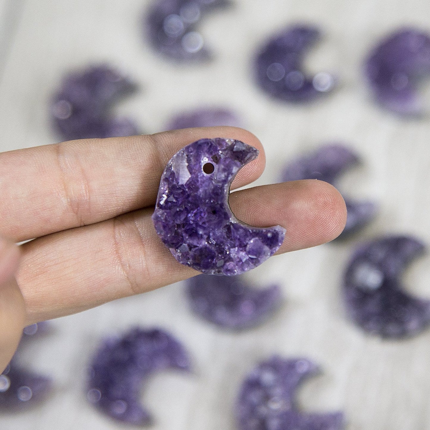 one drilled amethyst moon in a woman's hand.