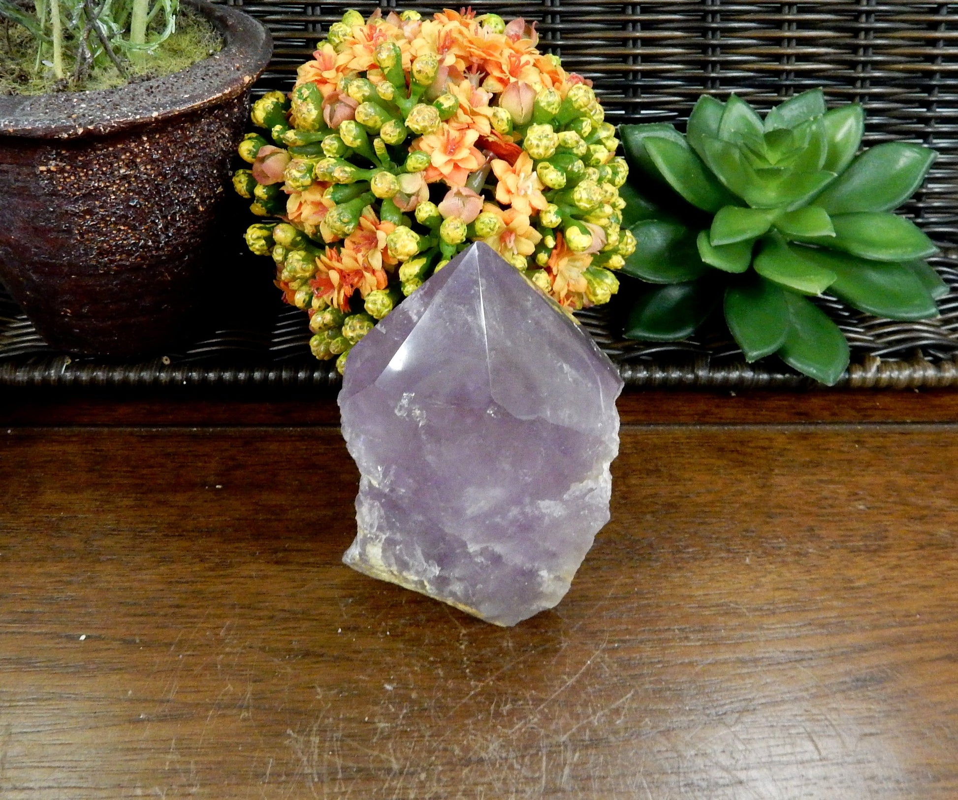 1 Raw Amethyst Semi Polished Point on wooden table with various decorations in the background
