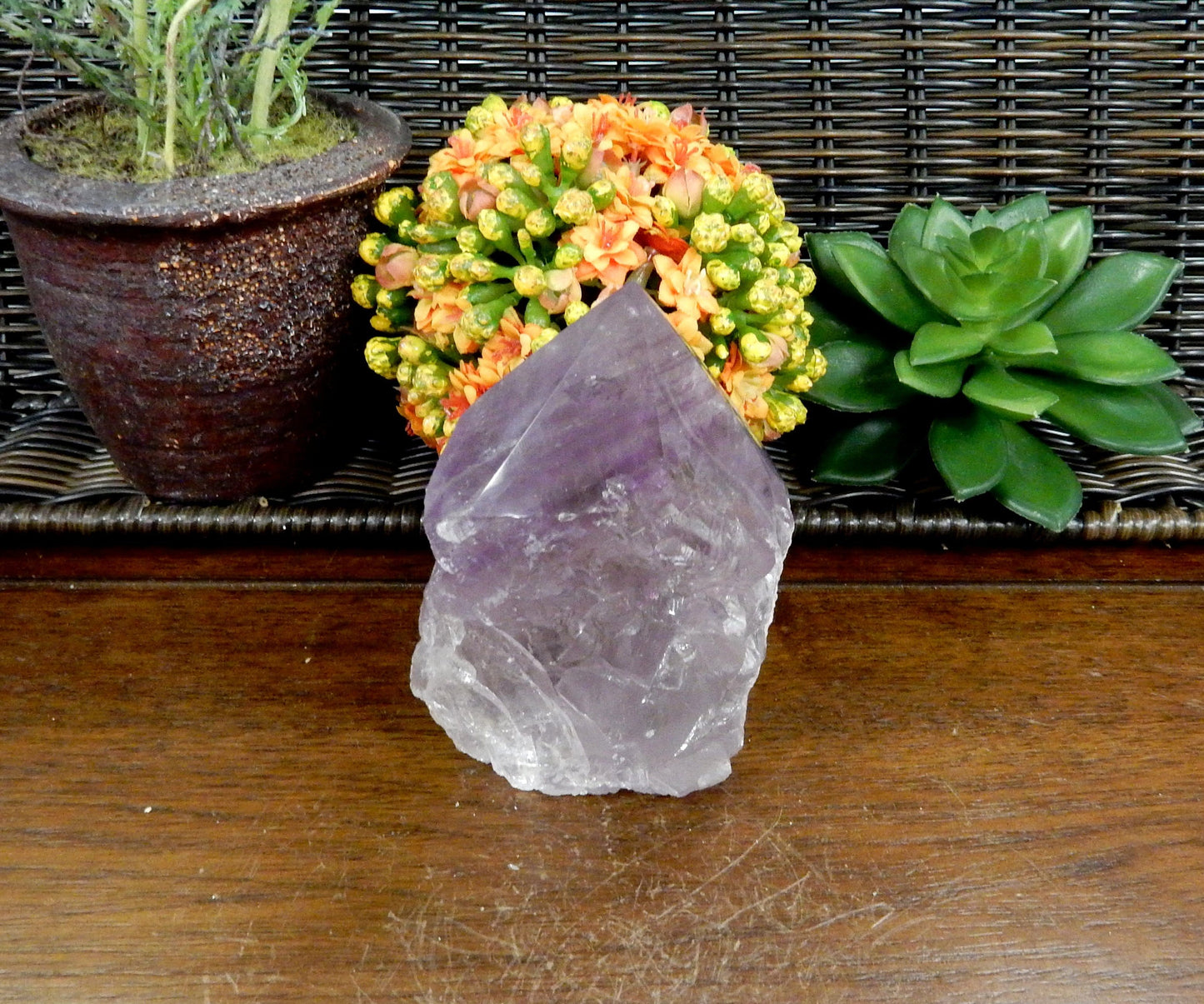 1 Raw Amethyst Semi Polished Point on wooden table with various decorations in the background