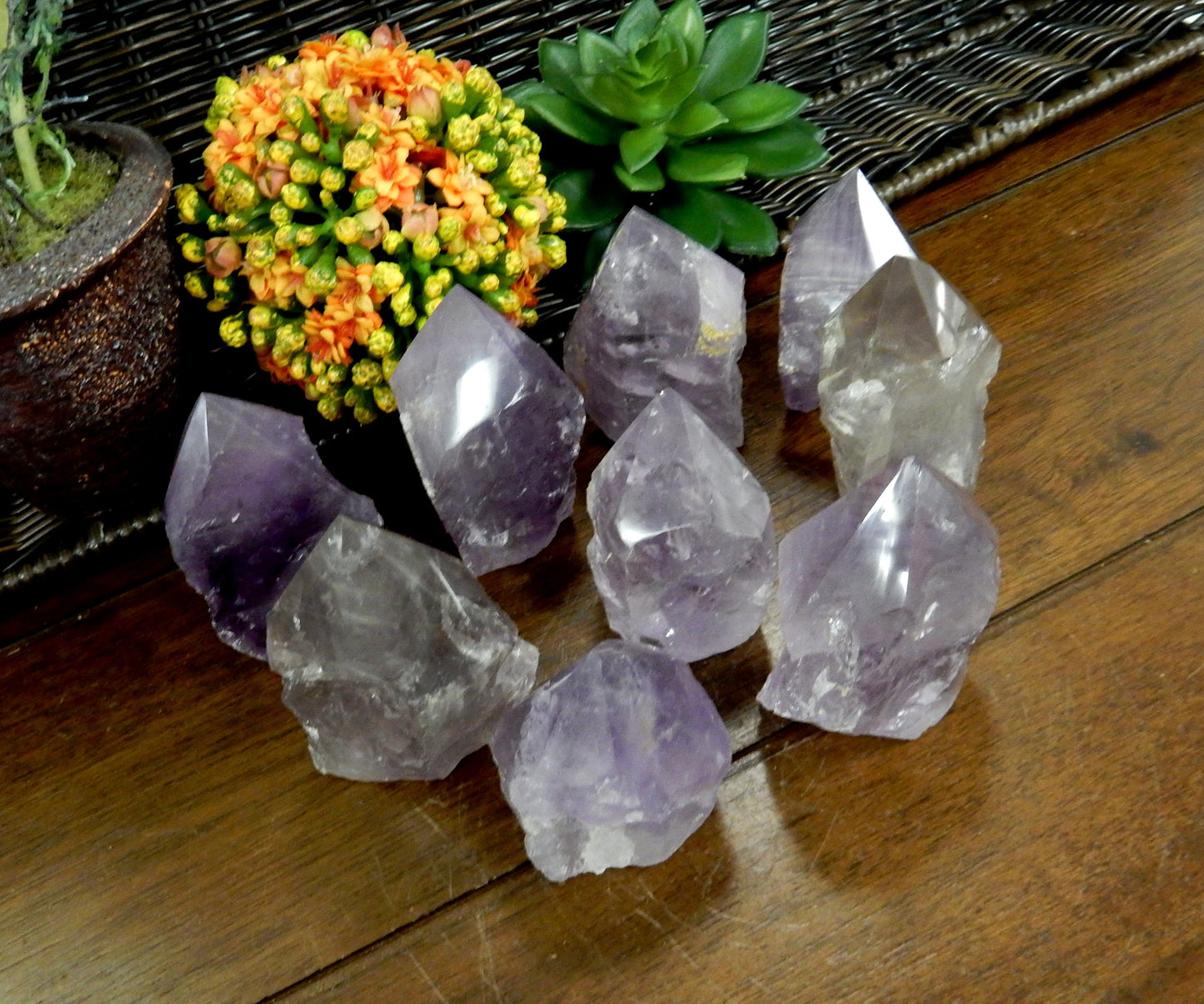 Angled top view of Raw Amethyst Semi Polished Points on wooden table with various decorations in the background
