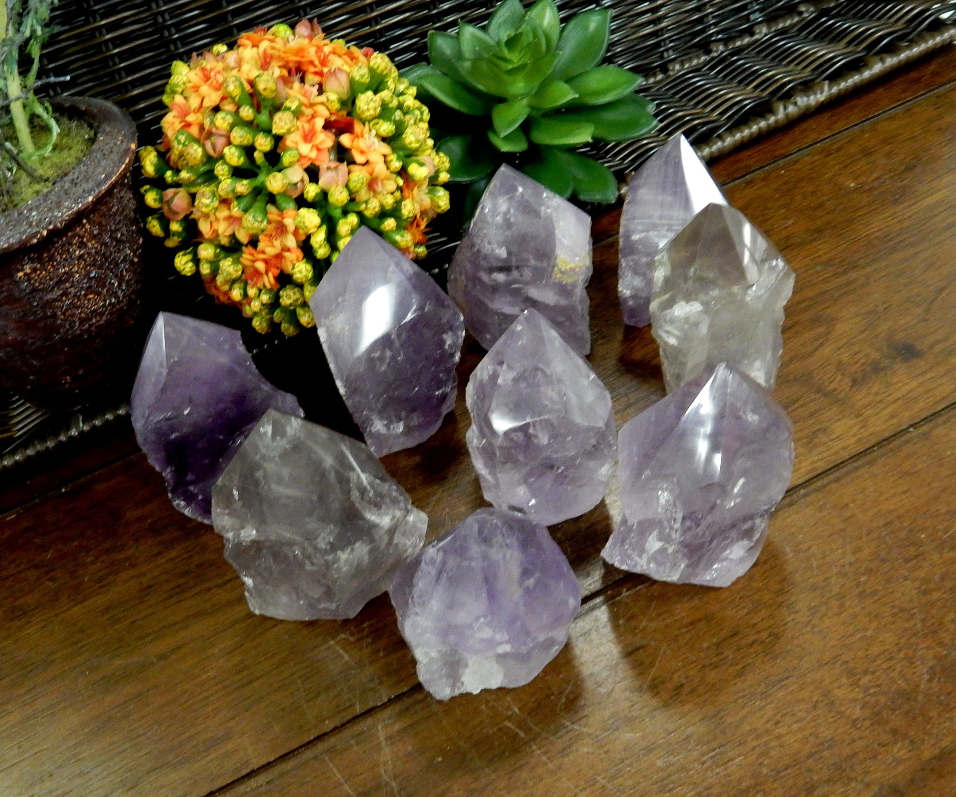 Angled top view of Raw Amethyst Semi Polished Points on wooden table with various decorations in the background