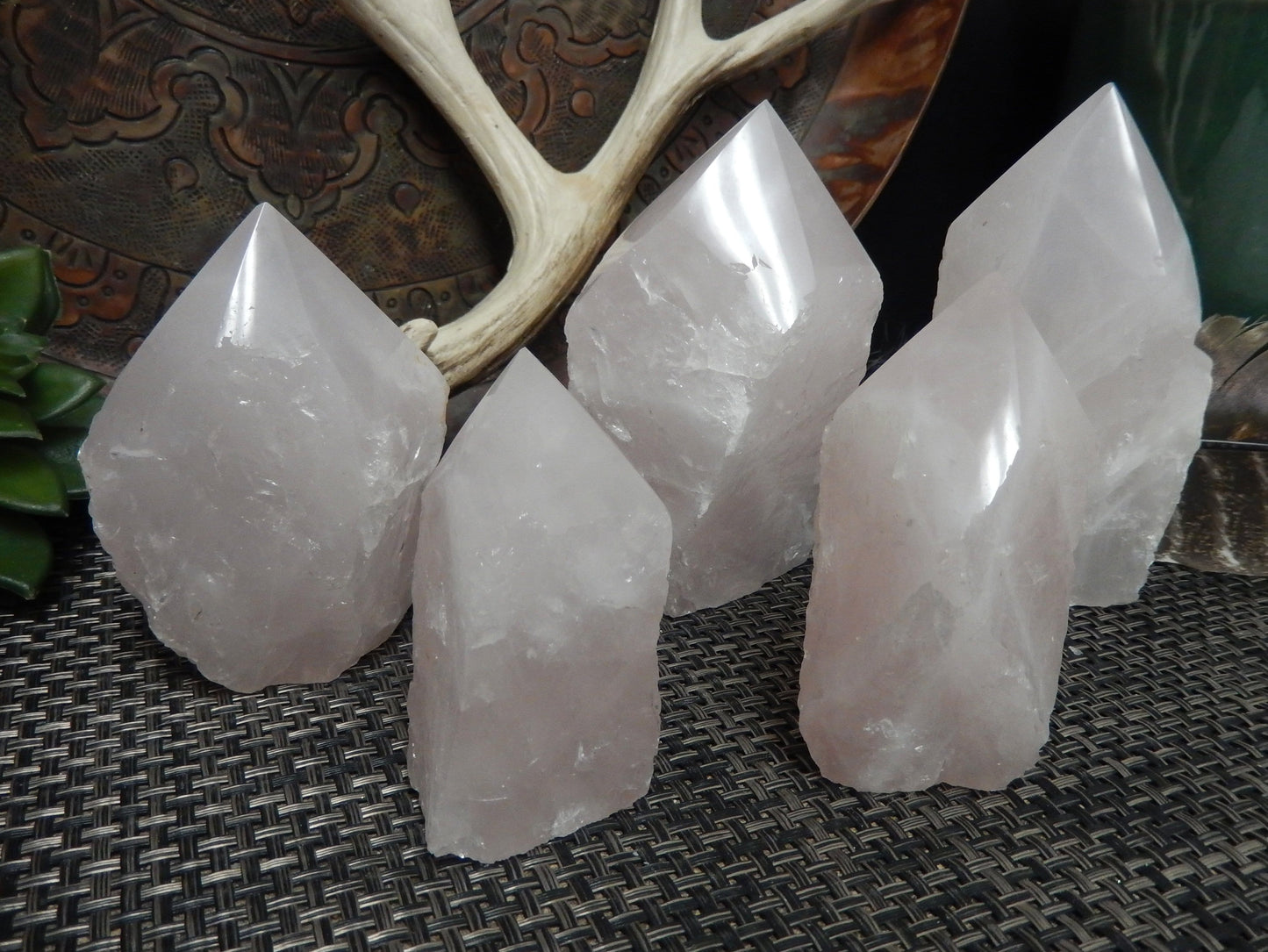 5 Rose Quartz Semi Polished Points of different sizes in front of decorations