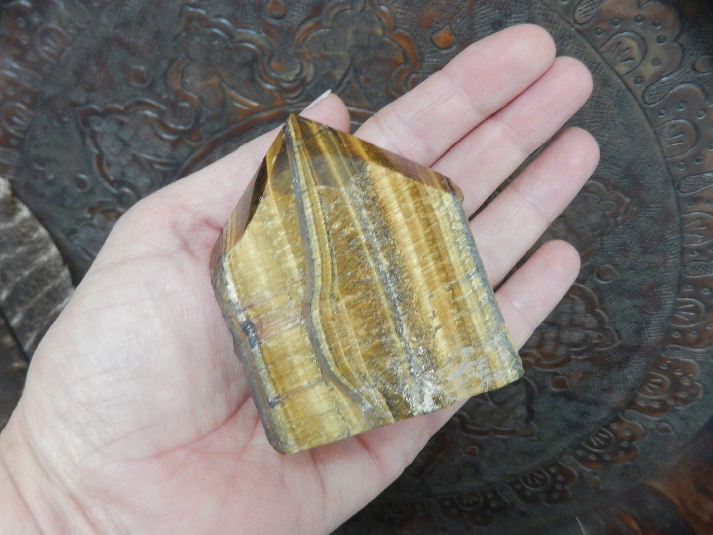 tiger eye polished point in a hand.