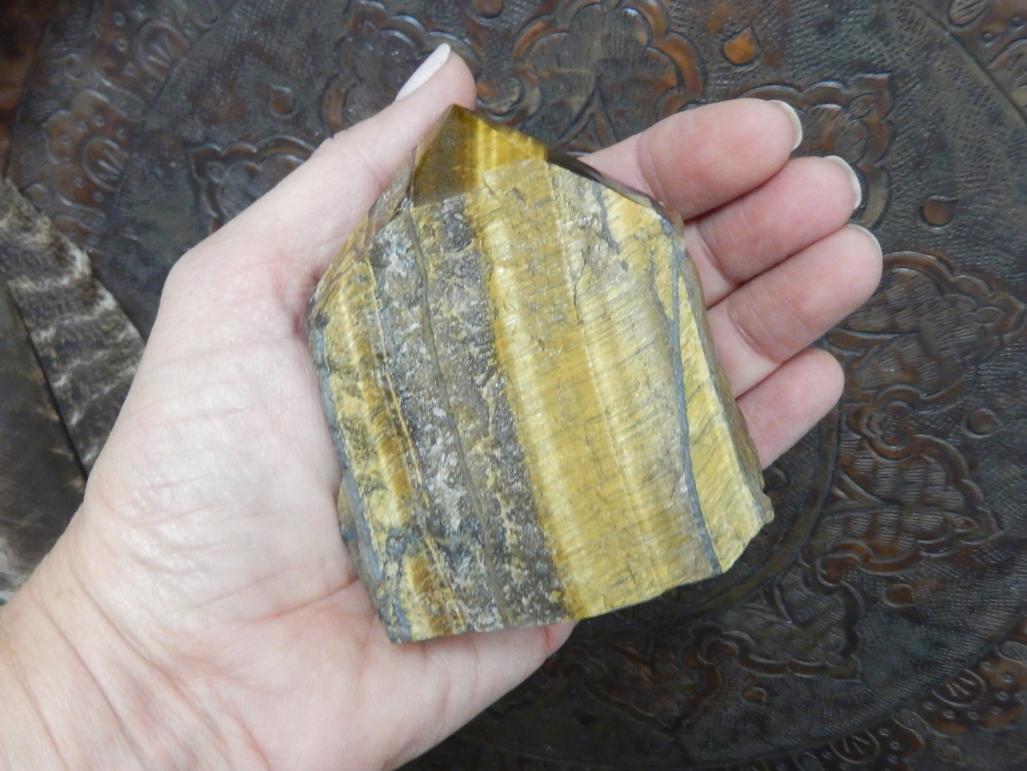 tiger eye polished point in a hand.