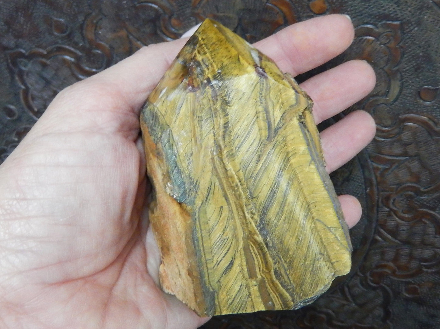 tiger eye polished point in a hand.