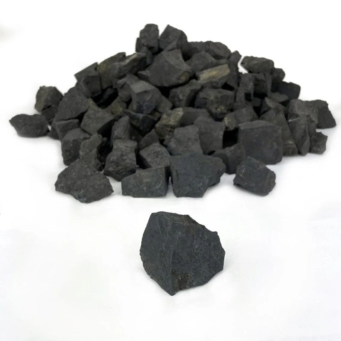close up of one shungite natural stone with a pile in the background