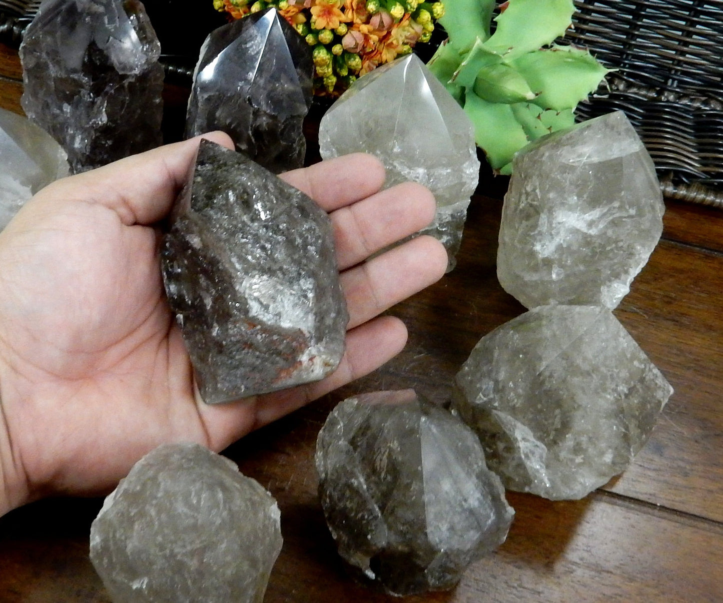 Hand holding up  Smokey Quartz Semi Polished Point with others in the background