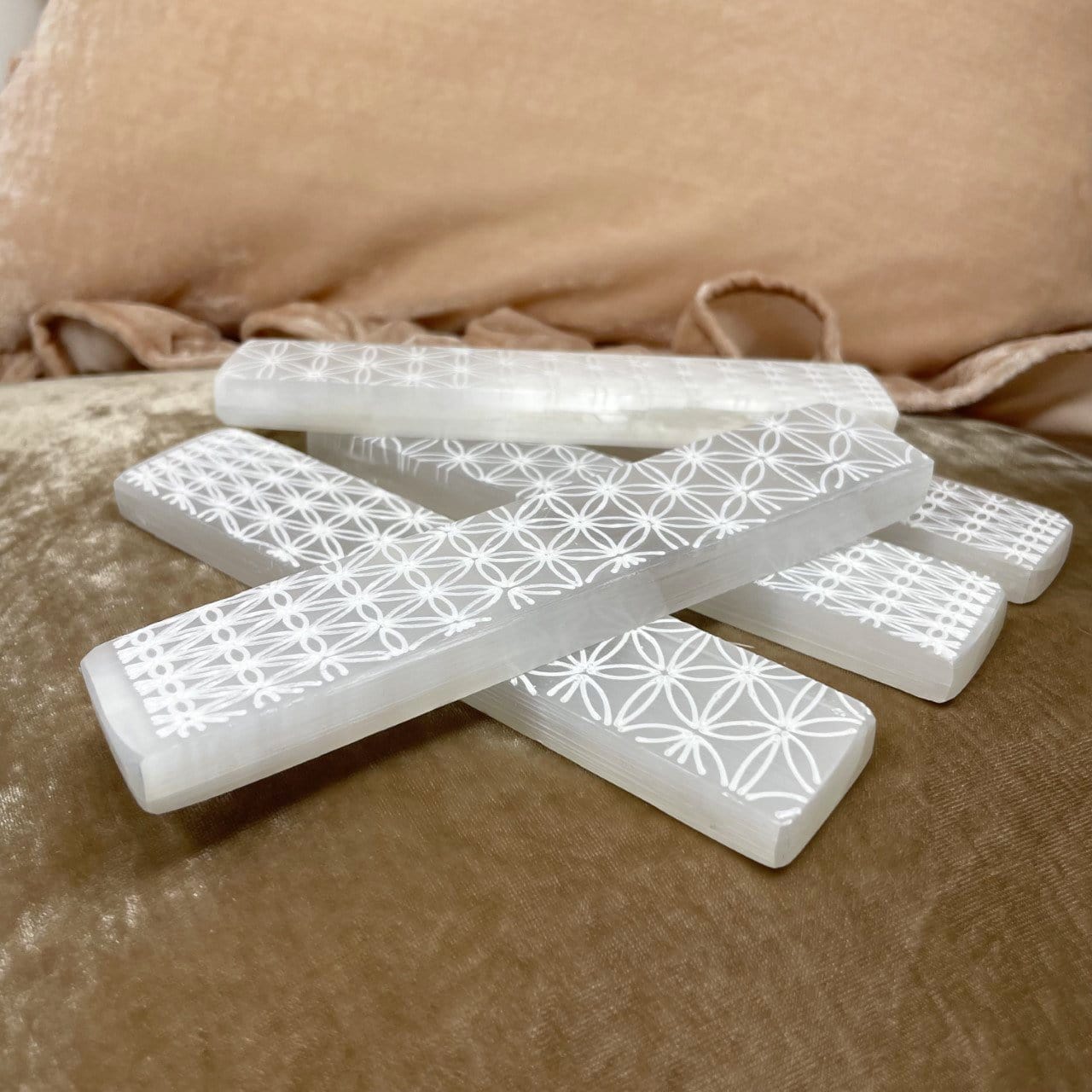 angled view of flower of life engraved selenite charging sticks for thickness