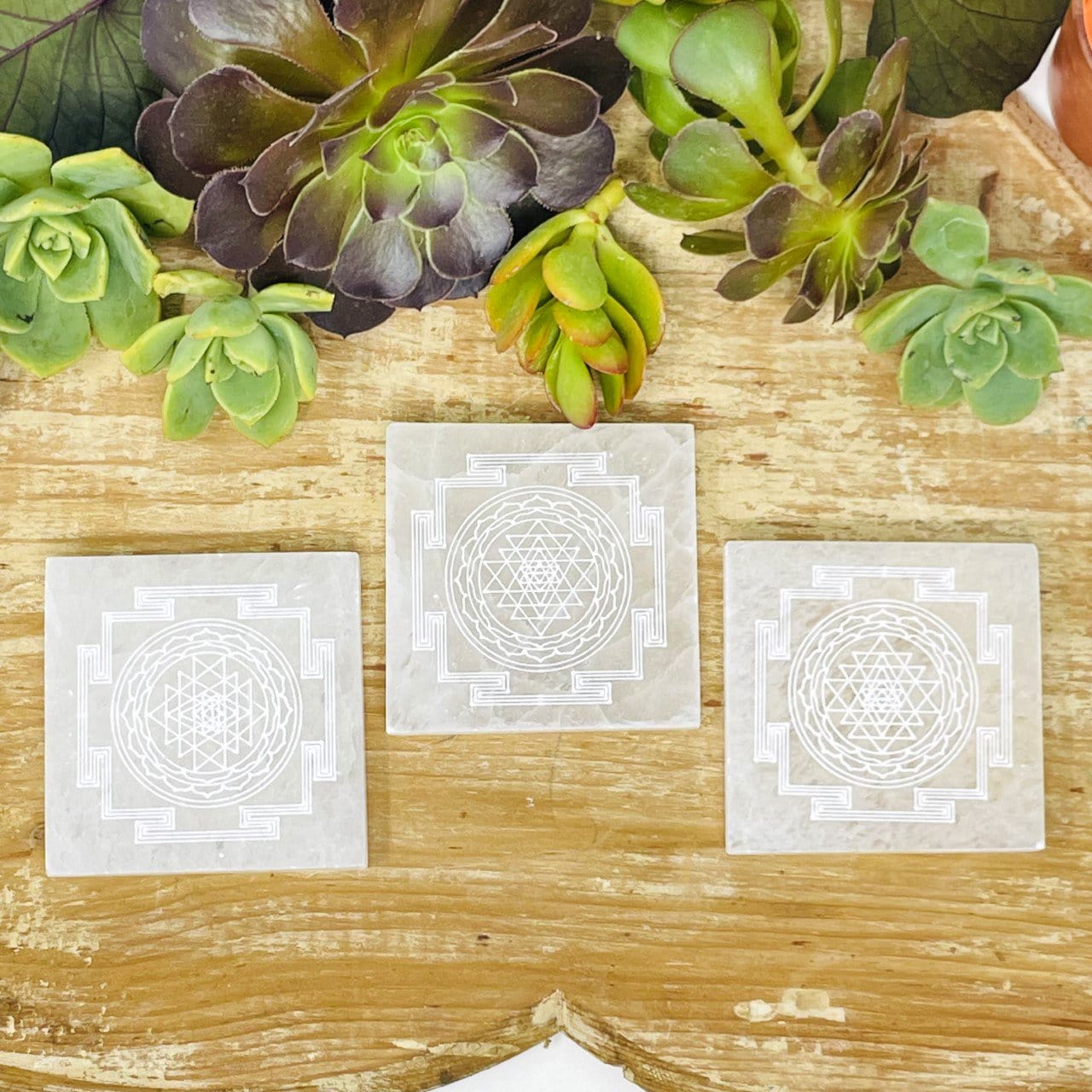 overhead view of selenite shri tantra mandala engraved square charging plates on display for engraving details